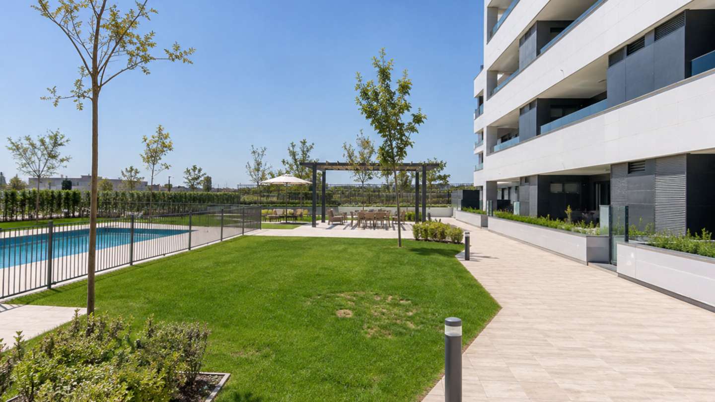 Urbanización de pisos con jardín y piscina comunitaria.